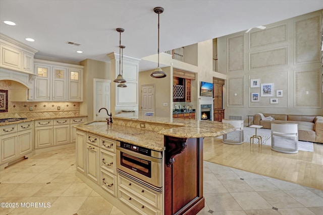 26 Bruns Rd, Allenhurst, NJ 07711 - kitchen featuring cream cabinetry, light tile patterned floors, a warm lit fireplace, decorative backsplash, and open floor plan