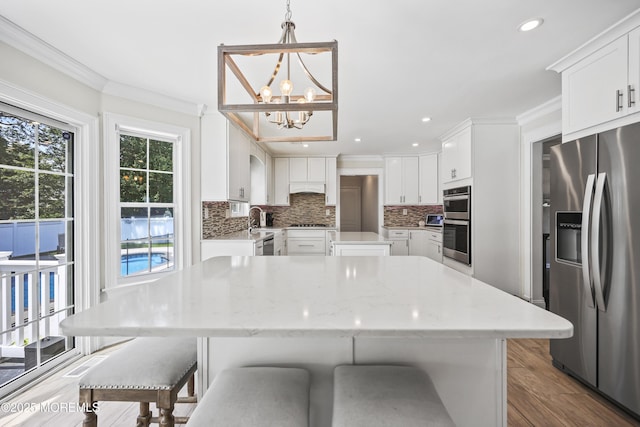304 Mackenzie Dr, Jackson, NJ 08527 - kitchen with appliances with stainless steel finishes, a chandelier, a kitchen island, a breakfast bar area, and ornamental molding