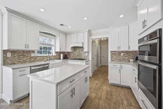 304 Mackenzie Dr, Jackson, NJ 08527 - kitchen with appliances with stainless steel finishes, light countertops, decorative backsplash, wood finished floors, and white cabinetry