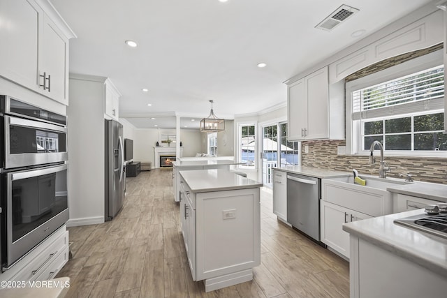 304 Mackenzie Dr, Jackson, NJ 08527 - kitchen featuring appliances with stainless steel finishes, a kitchen island, backsplash, light countertops, and white cabinetry