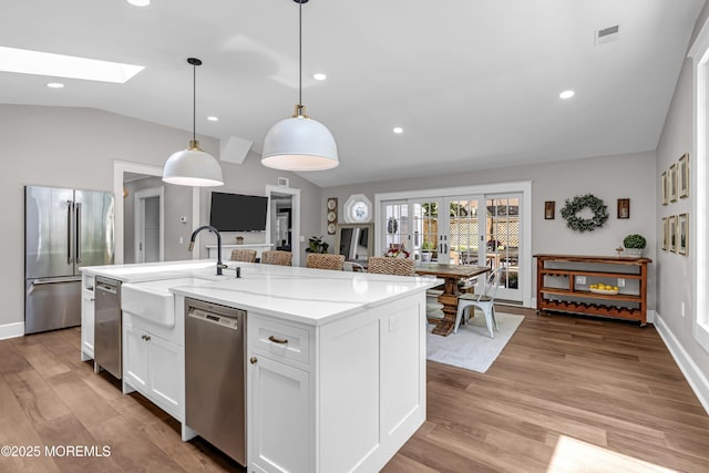 6 Buttonwood Dr, Shrewsbury Boro, NJ 07702 - kitchen with appliances with stainless steel finishes, vaulted ceiling, a skylight, light stone counters, and white cabinets