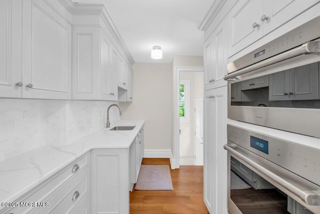 1905 3rd Ave, Spring Lake, NJ 07762 - kitchen with stainless steel oven, tasteful backsplash, light wood-style floors, and white cabinets