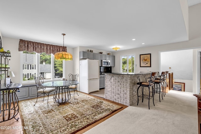 35 Tahoe Ln, Stafford, NJ 08050 - kitchen with freestanding refrigerator, gray cabinetry, stainless steel microwave, a breakfast bar, and hanging light fixtures