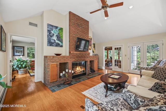6 Stoecker Rd, Holmdel, NJ 07733 - living area featuring high vaulted ceiling, a brick fireplace, a ceiling fan, wood finished floors, and french doors