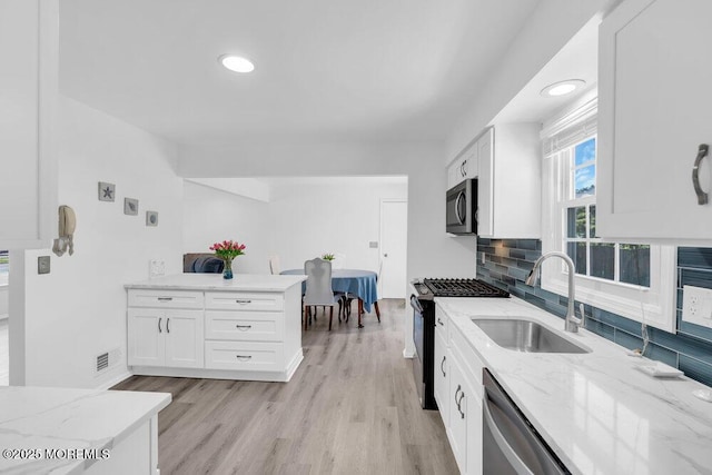 455 Drum Point Rd, Brick, NJ 08723 - kitchen with stainless steel appliances, white cabinetry, light stone counters, tasteful backsplash, and light wood-type flooring