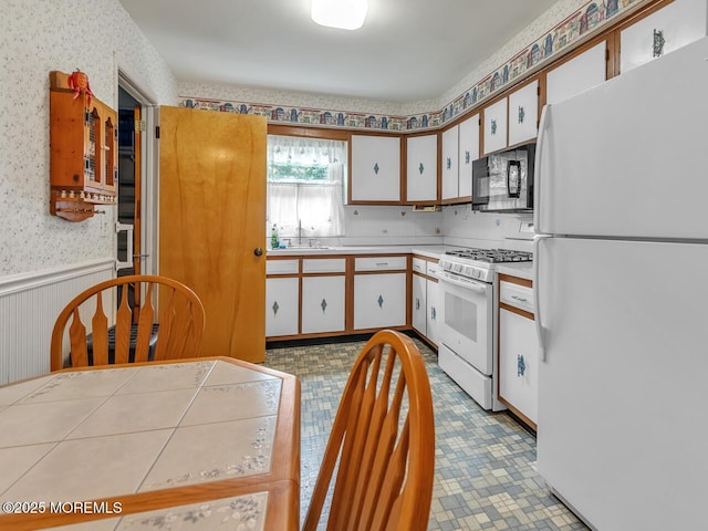 136 Georgetown Rd, Toms River, NJ 08757 - kitchen with white appliances, wallpapered walls, wainscoting, light countertops, and white cabinetry