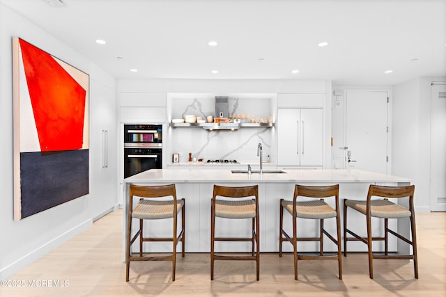 1101 Ocean Ave Unit 1404, Asbury Park, NJ 07712 - kitchen with light wood-style floors, recessed lighting, ventilation hood, an island with sink, and paneled fridge