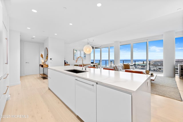1101 Ocean Ave Unit 1404, Asbury Park, NJ 07712 - kitchen with open floor plan, light wood-style flooring, white cabinetry, an island with sink, and dishwasher