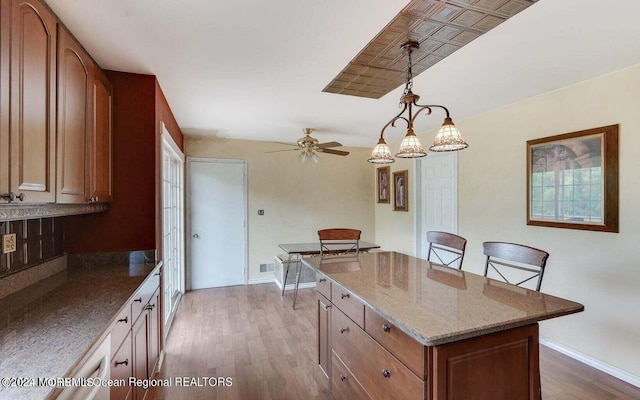 9 Tracy Pl, Jackson, NJ 08527 - kitchen with wood finished floors, light stone counters, a center island, a ceiling fan, and brown cabinetry