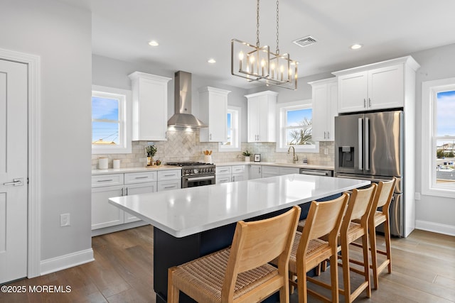 56 Gregg Dr, Beach Haven West, NJ 08050 - kitchen featuring appliances with stainless steel finishes, wall chimney exhaust hood, tasteful backsplash, a breakfast bar area, and white cabinetry