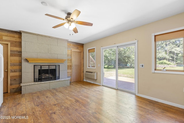 1792 Todd Rd, Toms River, NJ 08755 - unfurnished living room featuring wood walls, a wall unit AC, a tiled fireplace, ceiling fan, and wood finished floors