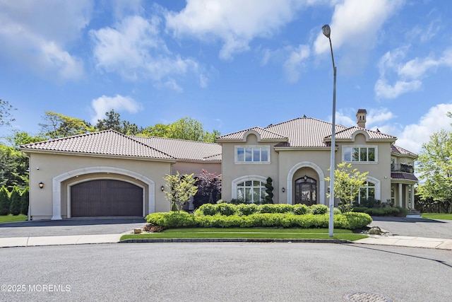 5 Champlain Ct, Lakewood, NJ 08701 - mediterranean / spanish home featuring a chimney, asphalt driveway, a tile roof, stucco siding, and an attached garage