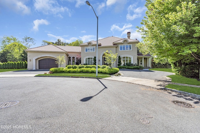 5 Champlain Ct, Lakewood, NJ 08701 - mediterranean / spanish-style house with a chimney, asphalt driveway, stucco siding, an attached garage, and a tiled roof
