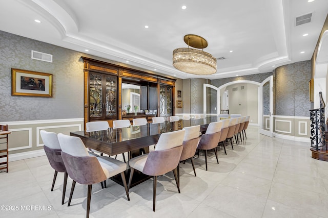 5 Champlain Ct, Lakewood, NJ 08701 - dining area with arched walkways, a decorative wall, a raised ceiling, wallpapered walls, and wainscoting
