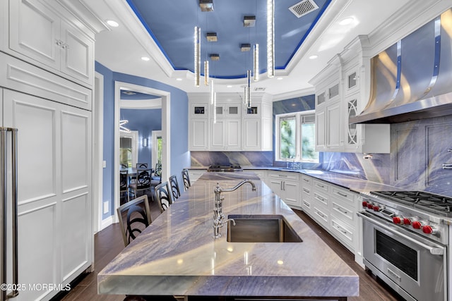5 Champlain Ct, Lakewood, NJ 08701 - kitchen featuring wall chimney exhaust hood, premium range, a kitchen island with sink, a raised ceiling, and white cabinetry