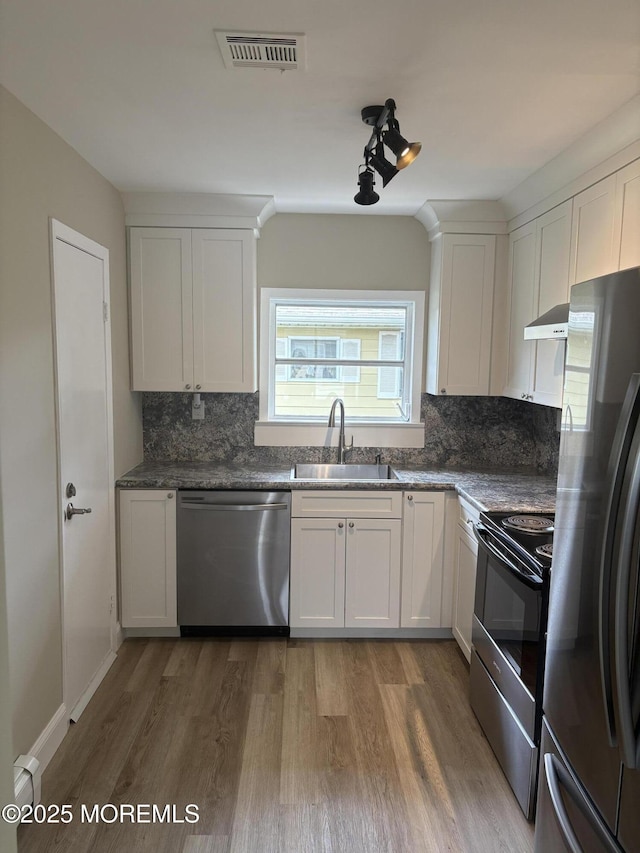 101 Bonaire Dr, Toms River, NJ 08757 - kitchen with stainless steel appliances, extractor fan, light wood-style flooring, backsplash, and white cabinetry