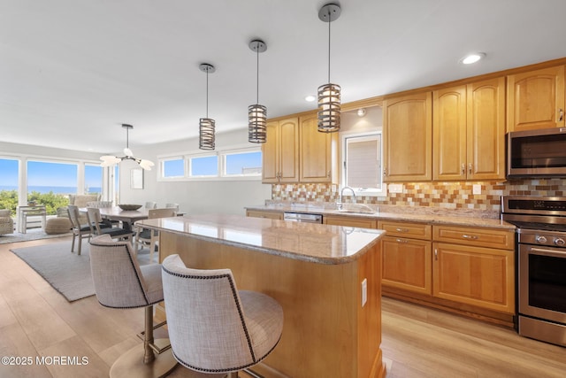 208 E 20th St, Long Beach Twp, NJ 08008 - kitchen with appliances with stainless steel finishes, a center island, light stone countertops, tasteful backsplash, and light wood-style floors