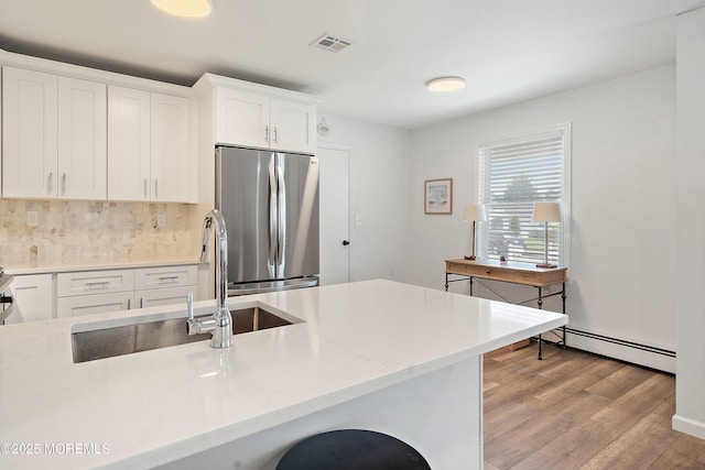 9 Maniwaki Ct, Toms River, NJ 08757 - kitchen with freestanding refrigerator, a baseboard heating unit, light wood-type flooring, decorative backsplash, and white cabinets