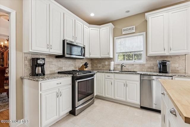 140 Palisade Dr, Freehold, NJ 07728 - kitchen featuring appliances with stainless steel finishes, white cabinets, decorative backsplash, light stone countertops, and recessed lighting