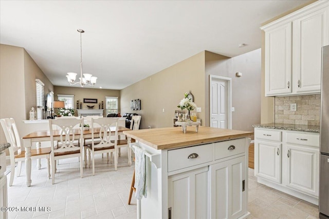 140 Palisade Dr, Freehold, NJ 07728 - kitchen with light tile patterned floors, a chandelier, white cabinets, backsplash, and pendant lighting