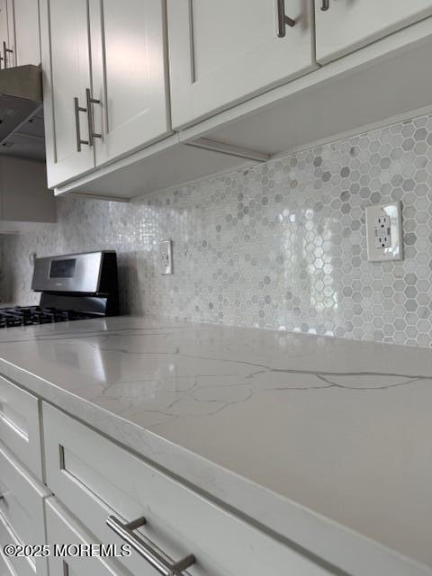 11 Ivy Rdg Unit 1000, Howell, NJ 07728 - kitchen with decorative backsplash, exhaust hood, light stone counters, white cabinets, and gas stove