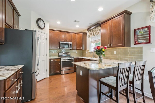259 Chickadee Ct Unit 1000, Freehold, NJ 07728 - kitchen with stainless steel appliances, a peninsula, light wood finished floors, light stone countertops, and decorative backsplash
