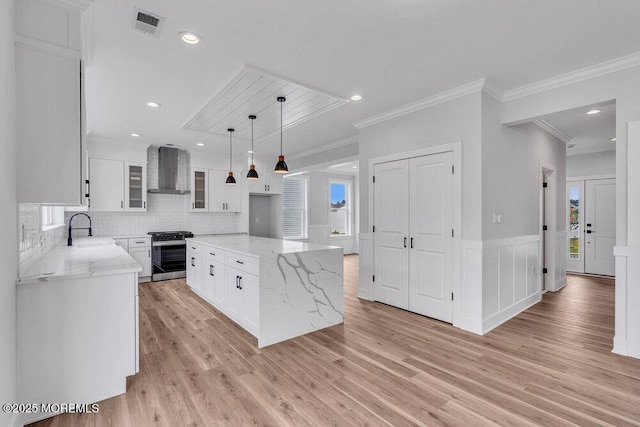 12 Outsail Ave, Barnegat, NJ 08005 - kitchen with stainless steel range with gas cooktop, wall chimney range hood, white cabinetry, light stone counters, and ornamental molding