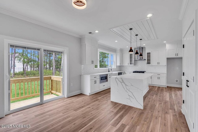 12 Outsail Ave, Barnegat, NJ 08005 - kitchen featuring stainless steel microwave, wall chimney exhaust hood, backsplash, white cabinetry, and crown molding