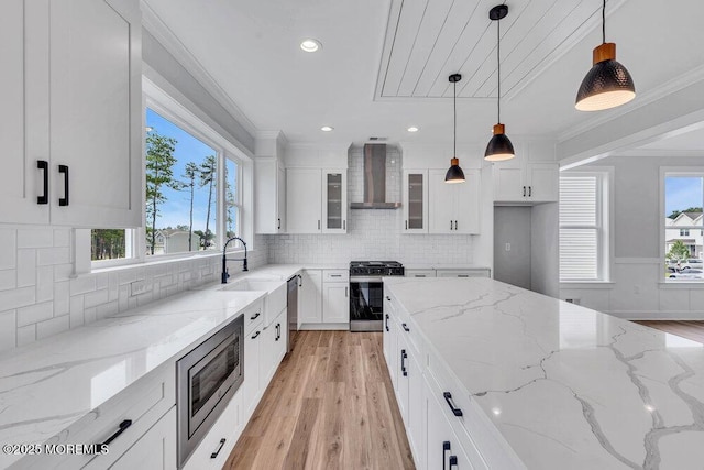 12 Outsail Ave, Barnegat, NJ 08005 - kitchen featuring appliances with stainless steel finishes, wall chimney exhaust hood, light wood-style floors, ornamental molding, and white cabinets