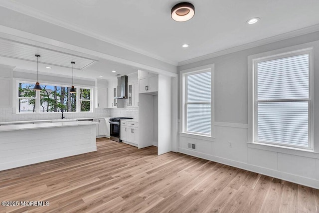 12 Outsail Ave, Barnegat, NJ 08005 - kitchen with stainless steel gas stove, wall chimney exhaust hood, light countertops, light wood finished floors, and tasteful backsplash