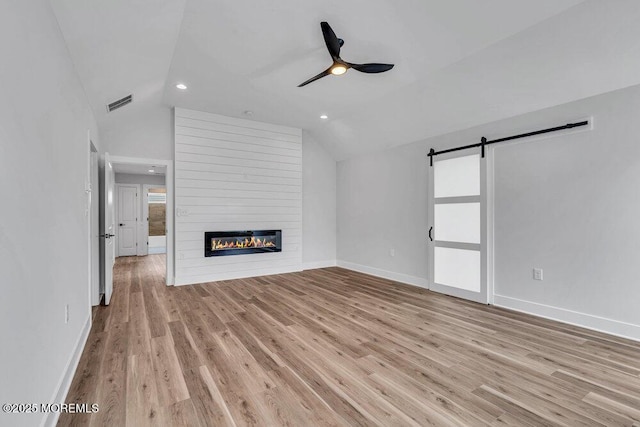 12 Outsail Ave, Barnegat, NJ 08005 - unfurnished living room featuring vaulted ceiling, a barn door, ceiling fan, light wood-style flooring, and a fireplace