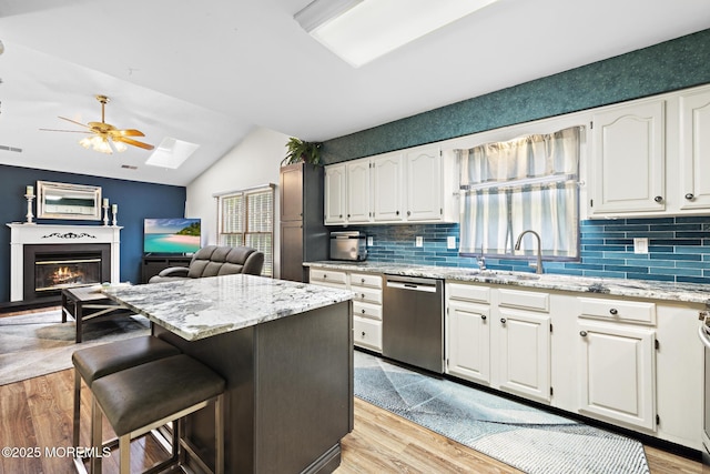 1887 Crimson Ct, Toms River, NJ 08755 - kitchen featuring dishwasher, a skylight, a glass covered fireplace, light wood finished floors, and lofted ceiling