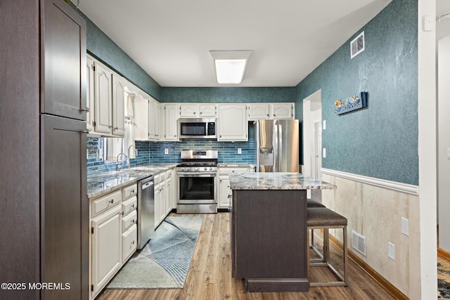 1887 Crimson Ct, Toms River, NJ 08755 - kitchen with stainless steel appliances, light wood finished floors, light stone counters, tasteful backsplash, and a wainscoted wall