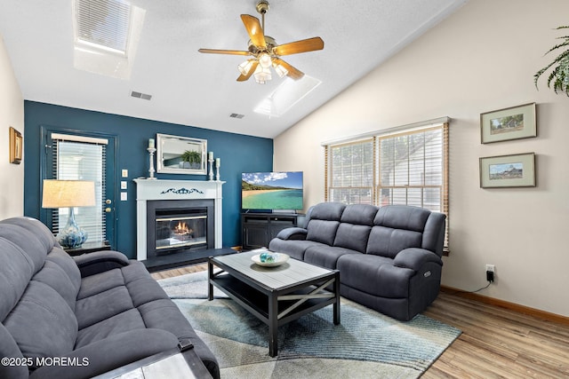 1887 Crimson Ct, Toms River, NJ 08755 - living area featuring a skylight, ceiling fan, vaulted ceiling, light wood-style floors, and a glass covered fireplace
