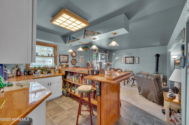 24 Roosevelt Dr, Brick, NJ 08724 - kitchen with white cabinetry, a wood stove, hanging light fixtures, light countertops, and light tile patterned flooring