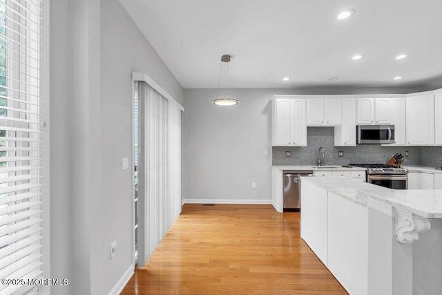 76 Deepwater Cir, Manalapan, NJ 07726 - kitchen with stainless steel appliances, light wood-type flooring, white cabinetry, tasteful backsplash, and light stone countertops
