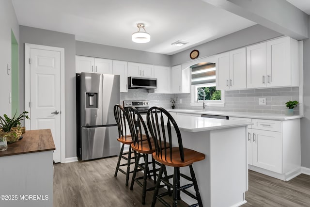 180 Grand Ave, Atlantic Highlands, NJ 07716 - kitchen with appliances with stainless steel finishes, wood finished floors, tasteful backsplash, and white cabinetry