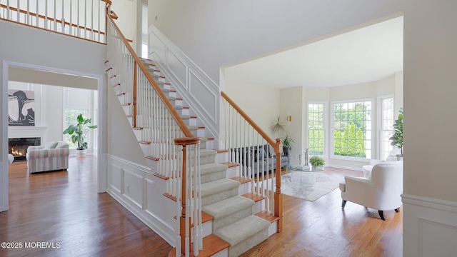 18 Sage St, Holmdel, NJ 07733 - stairway with wood finished floors, a decorative wall, and a warm lit fireplace