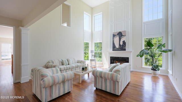 18 Sage St, Holmdel, NJ 07733 - living room featuring a high ceiling, a fireplace, decorative columns, and dark wood-style flooring