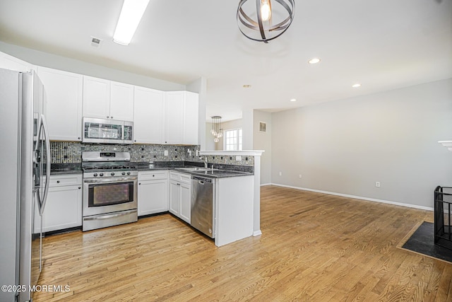 9 Mioduski Ct, Parlin, NJ 08859 - kitchen with appliances with stainless steel finishes, dark countertops, a peninsula, backsplash, and light wood finished floors