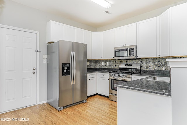 9 Mioduski Ct, Parlin, NJ 08859 - kitchen featuring appliances with stainless steel finishes, light wood-style flooring, tasteful backsplash, and white cabinetry