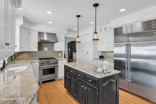 1510 Bel Aire Ct E, Point Pleasant, NJ 08742 - kitchen featuring high end appliances, wall chimney range hood, white cabinetry, dark cabinetry, and arched walkways