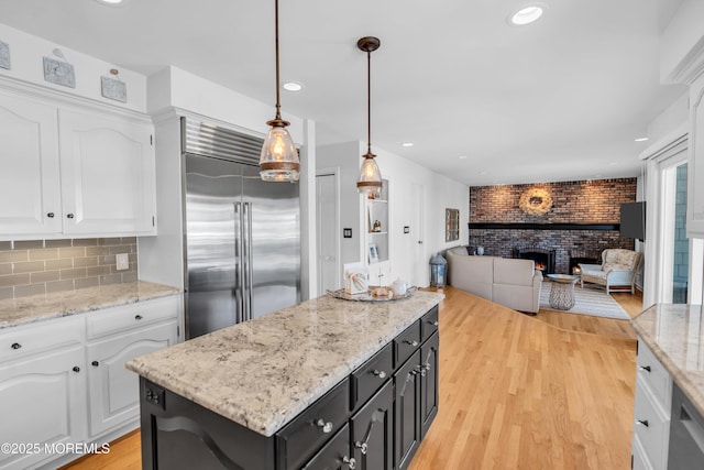1510 Bel Aire Ct E, Point Pleasant, NJ 08742 - kitchen with built in fridge, white cabinetry, brick wall, a center island, and a brick fireplace