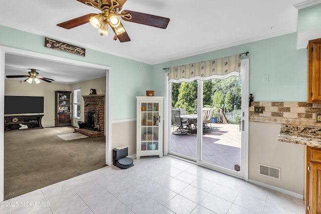 70 Desai Ct, Freehold, NJ 07728 - doorway to outside with a ceiling fan, a brick fireplace, light tile patterned flooring, ornamental molding, and light colored carpet