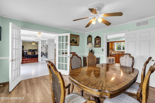 70 Desai Ct, Freehold, NJ 07728 - dining room featuring french doors, ceiling fan, a chandelier, ornamental molding, and light wood-style flooring