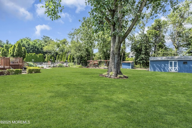 70 Desai Ct, Freehold, NJ 07728 - view of grassy yard with a playground, a storage unit, a deck, and view of wooded area