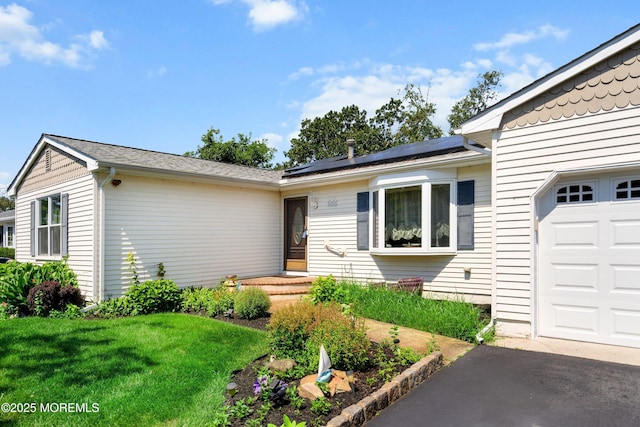 620 Pacific Ave, Beachwood, NJ 08722 - entrance to property featuring an attached garage, roof mounted solar panels, a yard, and asphalt driveway