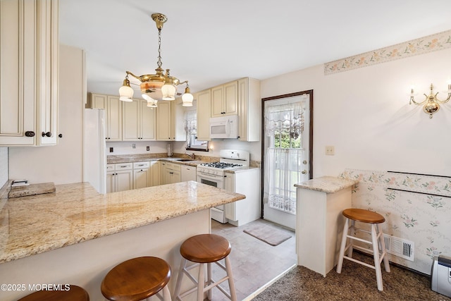620 Pacific Ave, Beachwood, NJ 08722 - kitchen with white appliances, cream cabinetry, a chandelier, light stone countertops, and a peninsula