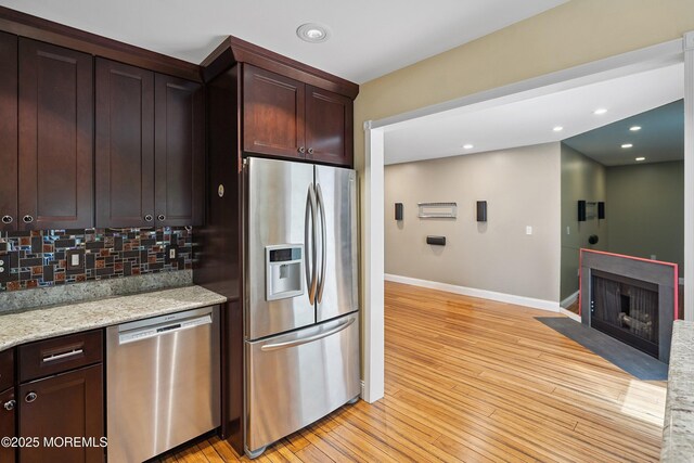 13 Jill Ct, Franklin Twp, NJ 08873 - kitchen with stainless steel appliances, light wood-style floors, decorative backsplash, a fireplace with flush hearth, and dark brown cabinetry