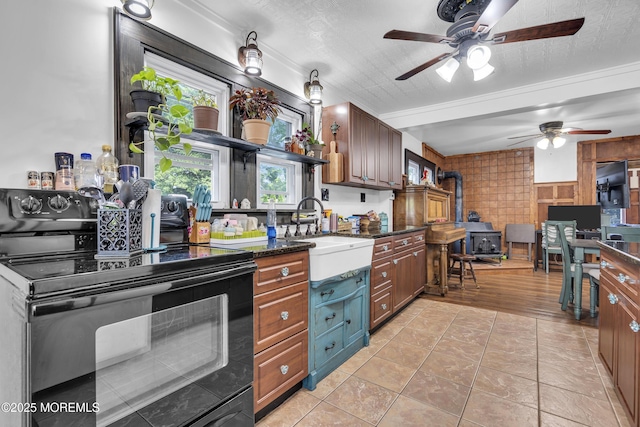 614 Bay Blvd, Bayville, NJ 08721 - kitchen with black electric range oven, a wood stove, a ceiling fan, dark stone counters, and light tile patterned floors